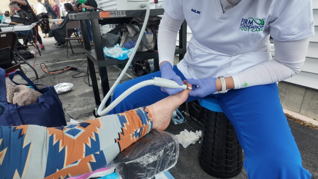 Gail Hackelberg, RN, providing mobile foot care to a woman during a Cuts 4 Christ outreach event in Maine. A close-up of foot care in progress at a community clinic.
