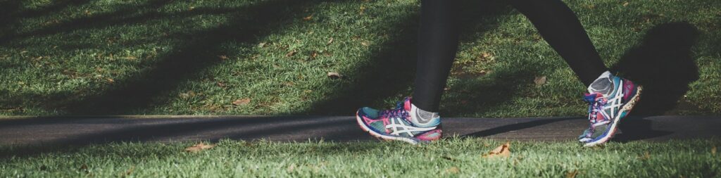 shallow focus photography of person walking on road between grass