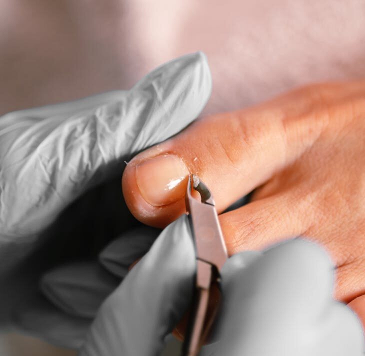 Close-up of a professional pedicure treatment using cuticle tongs